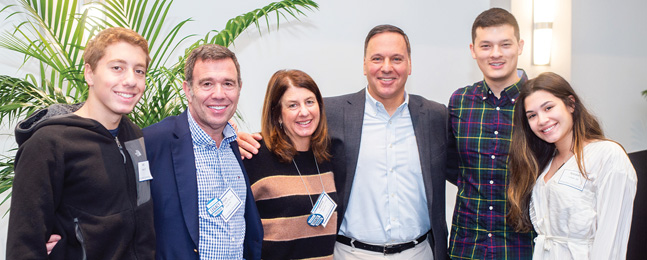 The Brandeis president and five people from a range of generations smile for the camera